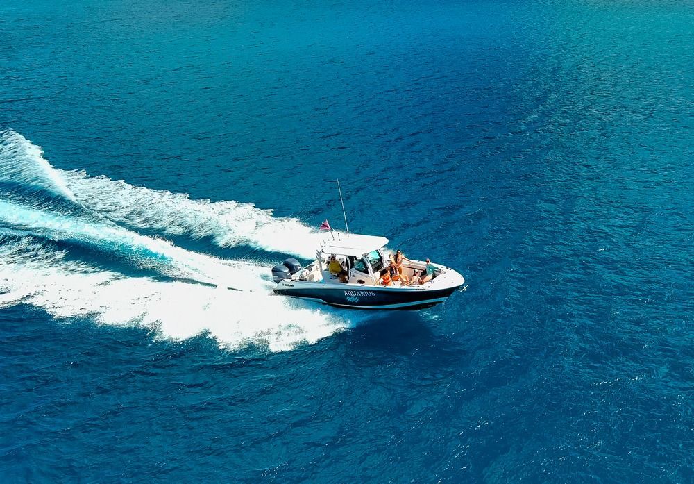 A white boat is floating in the water near a beach