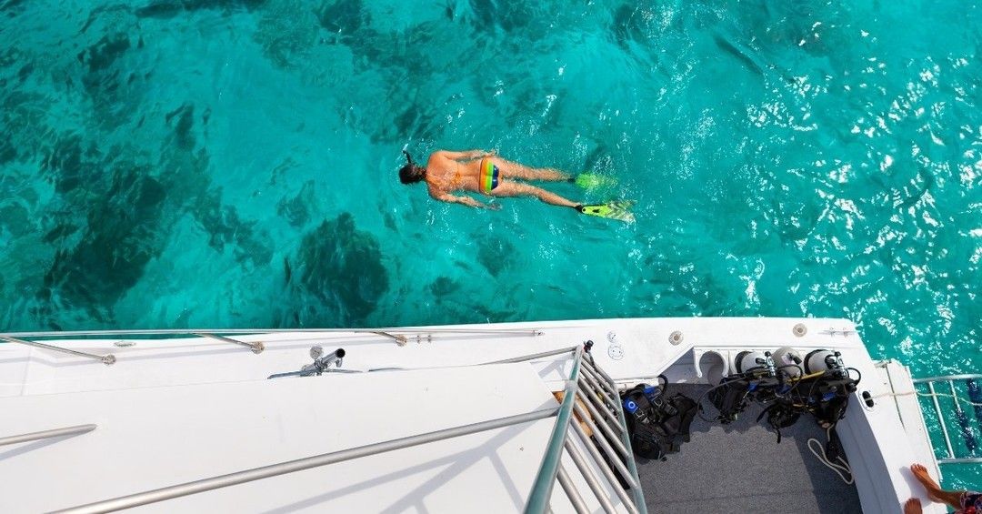 A man is swimming in the ocean on a boat.