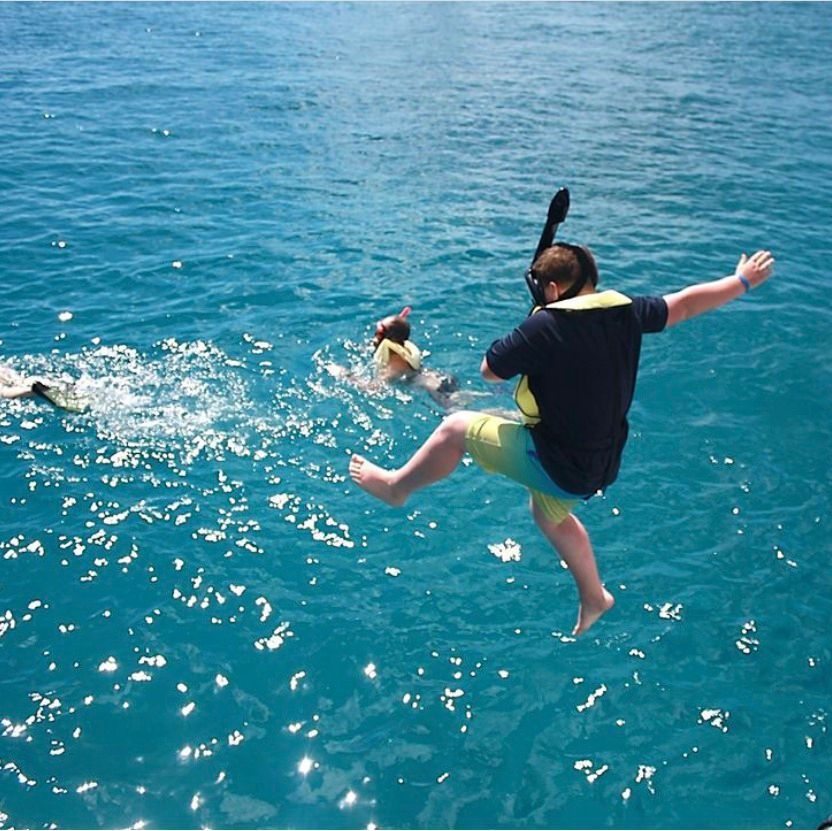 A man wearing a life jacket is jumping into the ocean