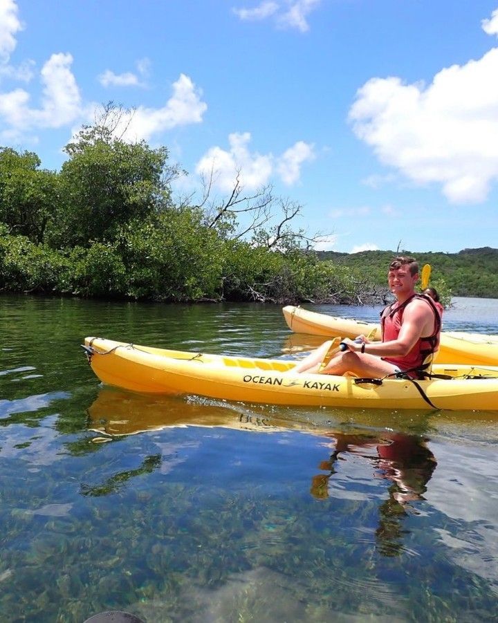 A man is sitting in a yellow kayak on a river.