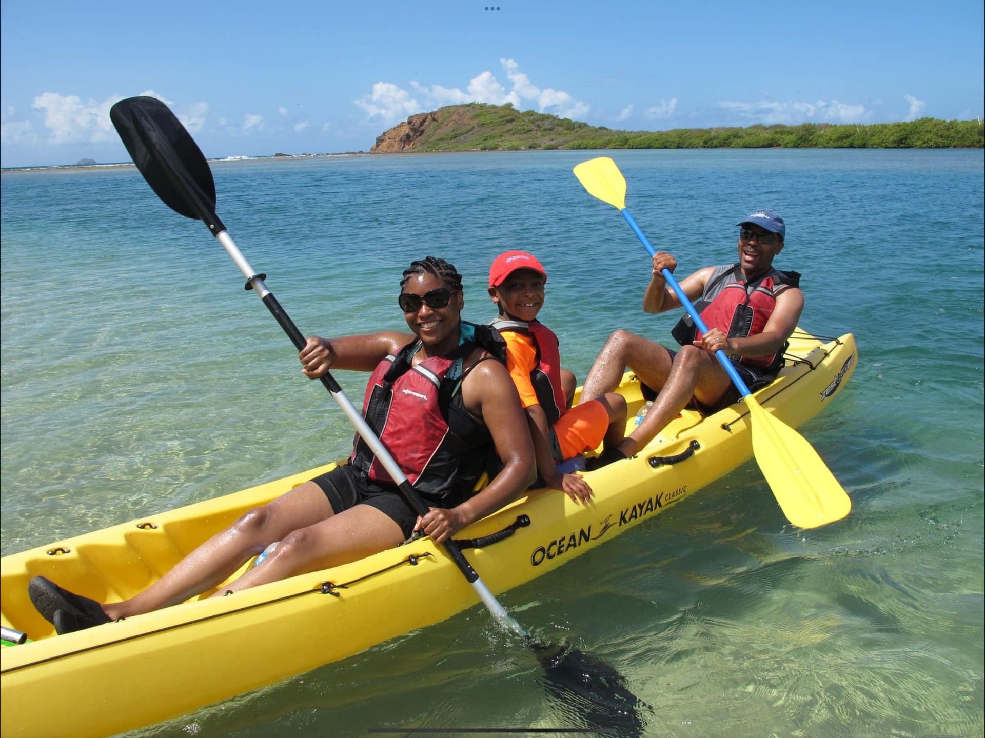 Three people are in a yellow kayak in the water.