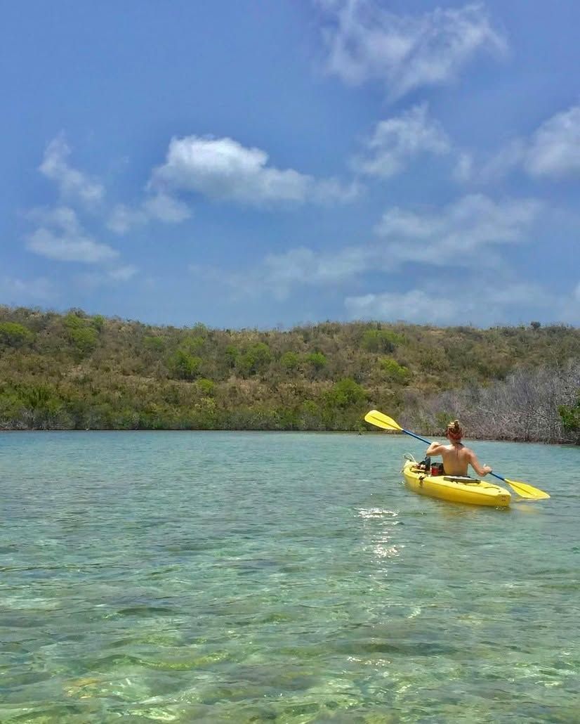 A man is paddling a yellow kayak on a lake.