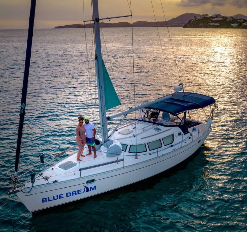 A couple standing on the deck of a blue dream sailboat