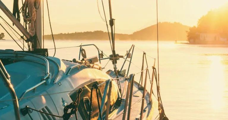 A sailboat is docked in the water at sunset.