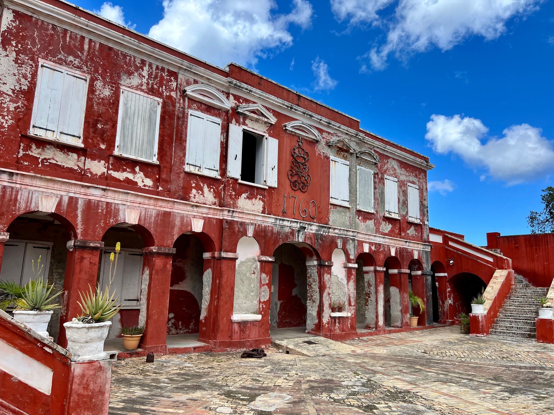 A large white building with arches and stairs is on the corner of a street.