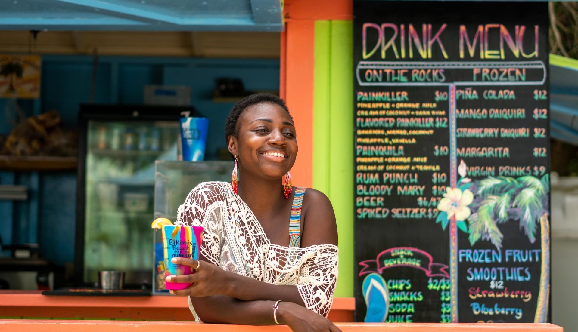 A woman is sitting at a counter in front of a drink menu.