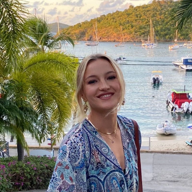 A woman is standing in front of a body of water with boats in it.