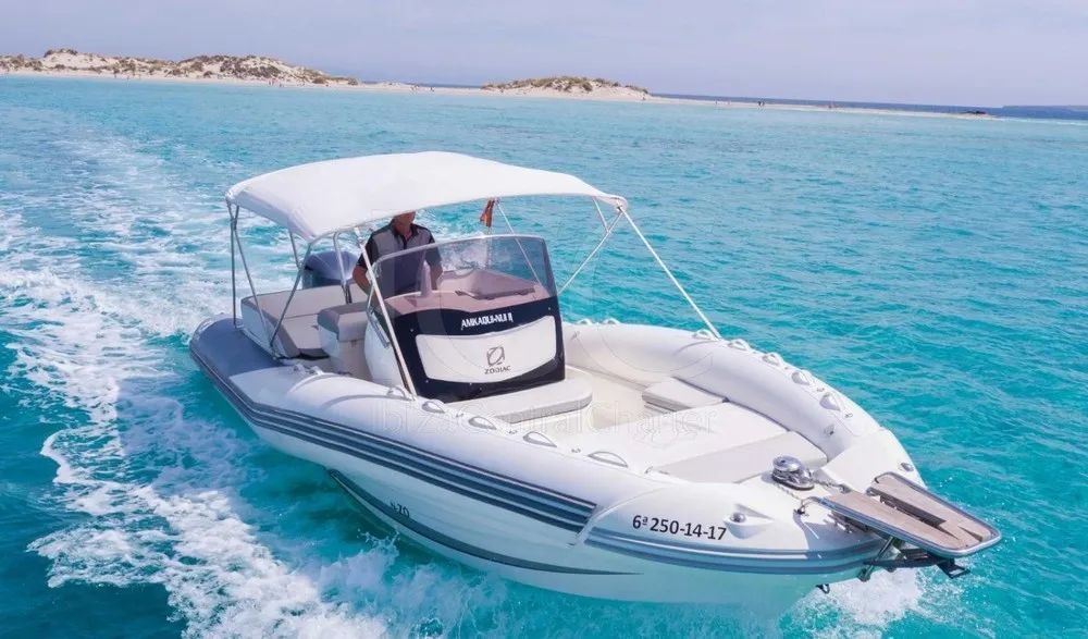 A white boat with a canopy is floating on top of a body of water.