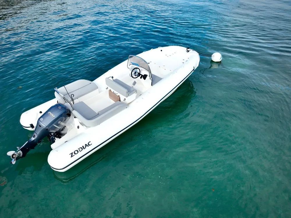 A white zodiac boat is floating on top of a body of water