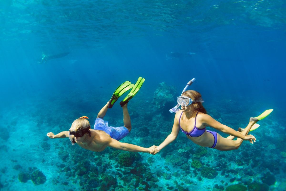 A man and a woman are holding hands while swimming in the ocean.