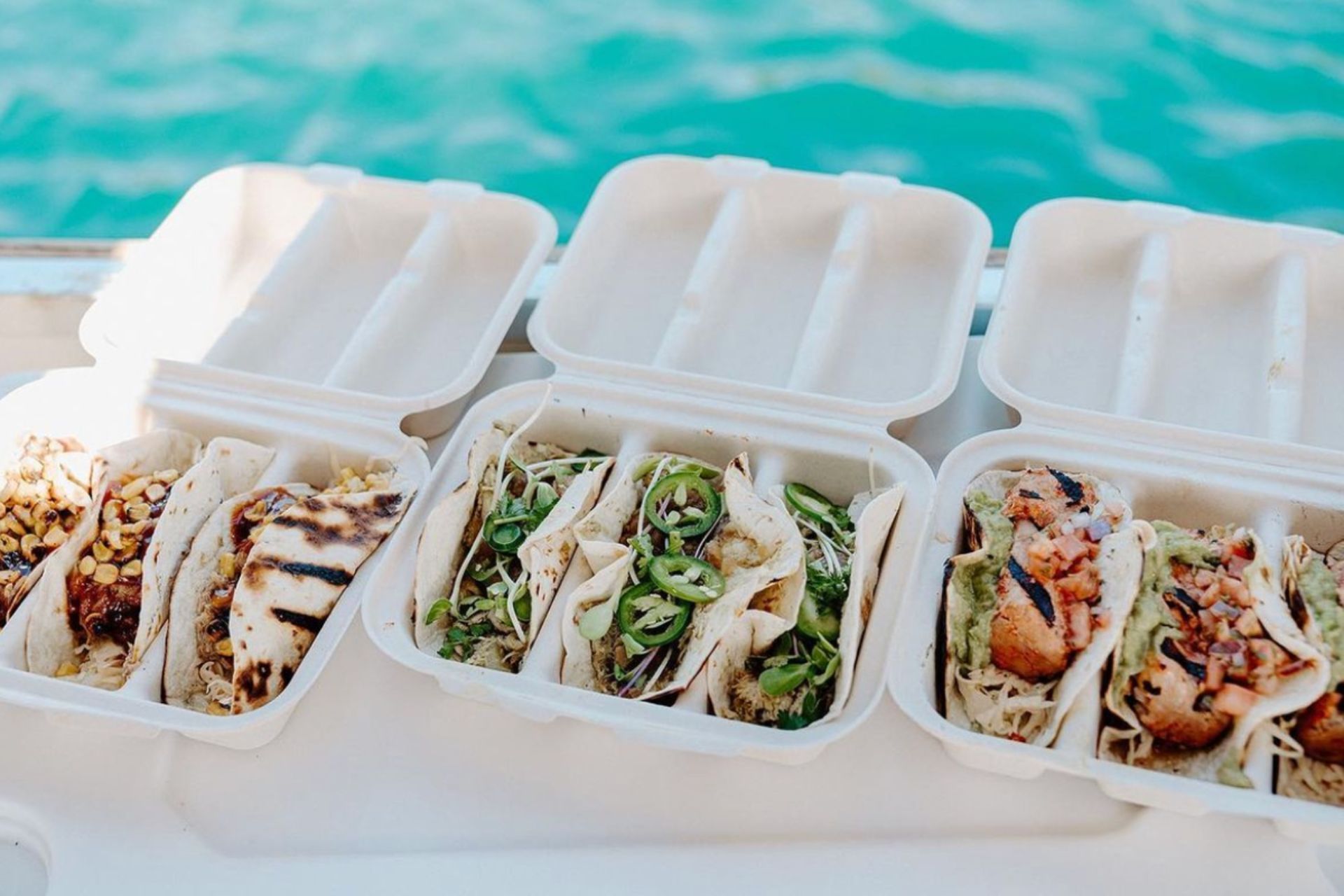 A row of styrofoam containers filled with food on a boat.