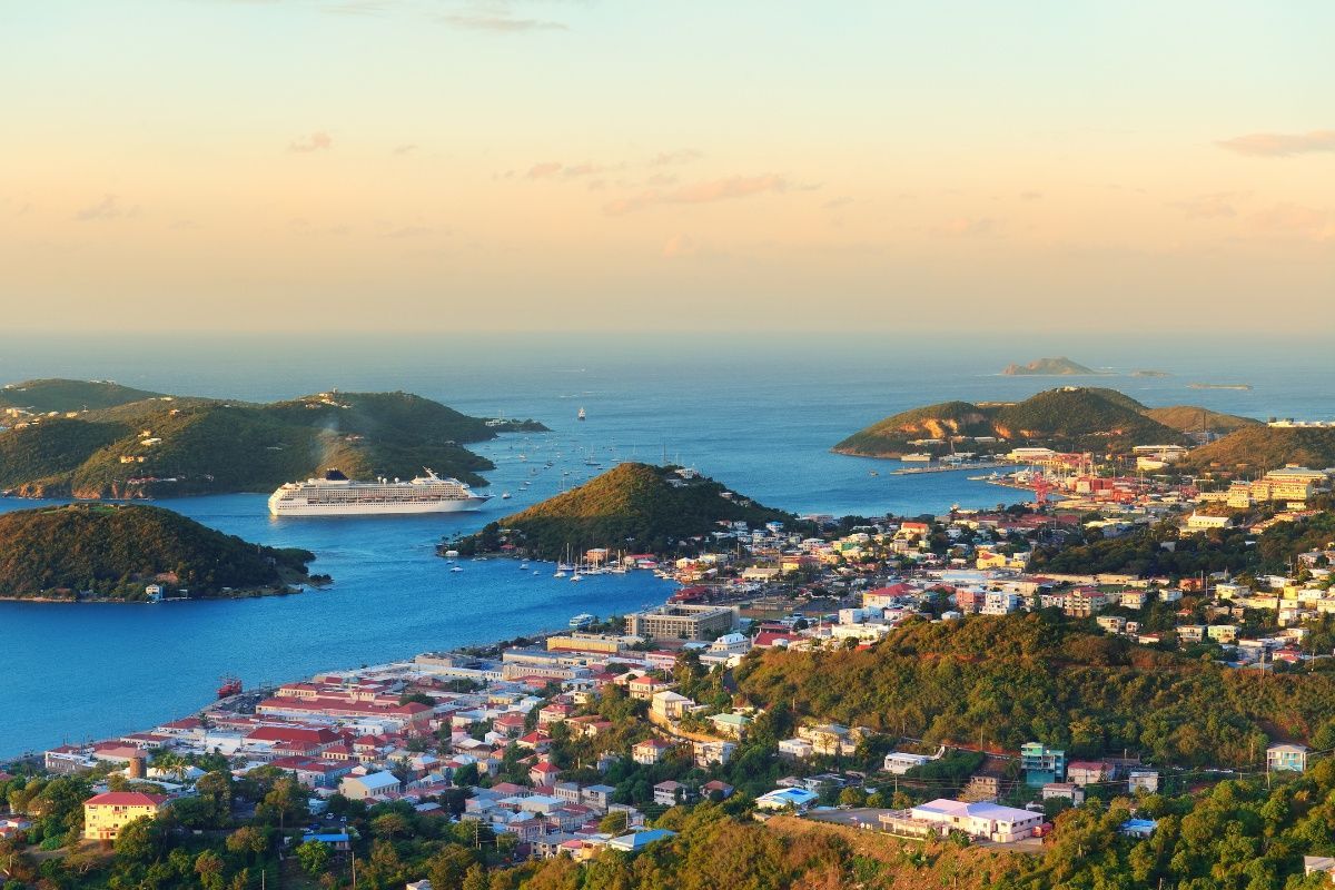 An aerial view of a city and a large body of water with a cruise ship in the distance.