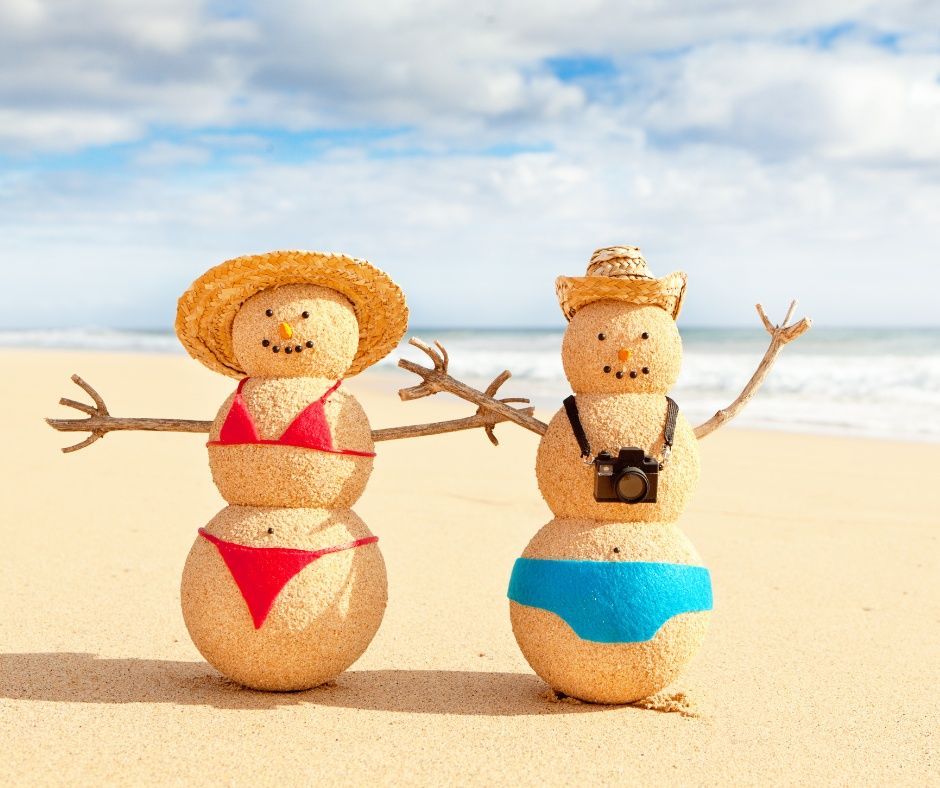 Two snowmen wearing bikinis and hats are standing on the beach