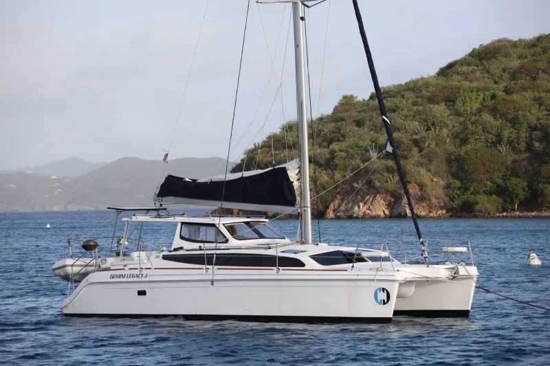 A white sailboat is floating on top of a body of water.