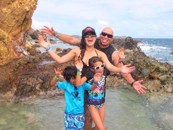 A group of people are swimming in the water holding shells and giving a thumbs up.