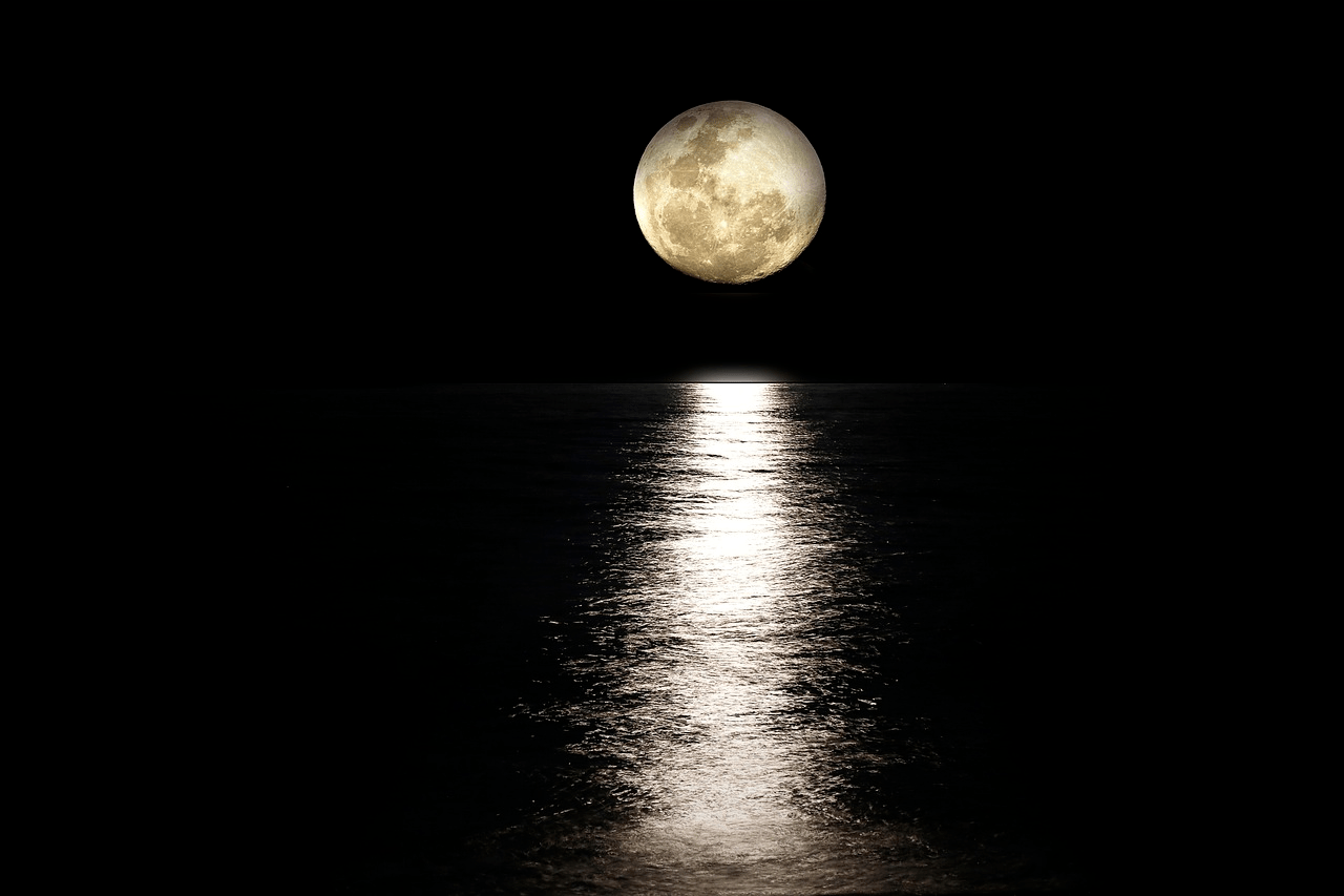 A full moon is reflected in the water at night.