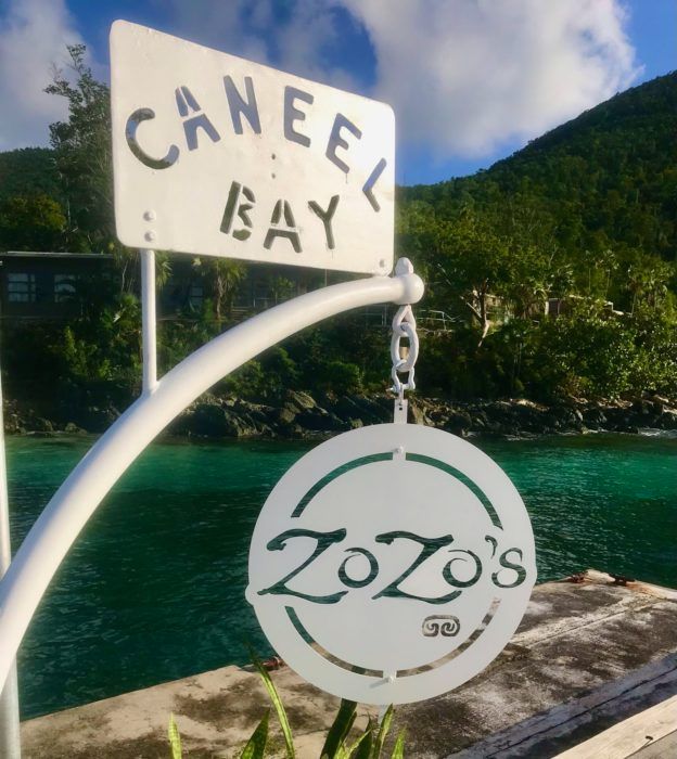 A sign for canee bay hangs over a body of water