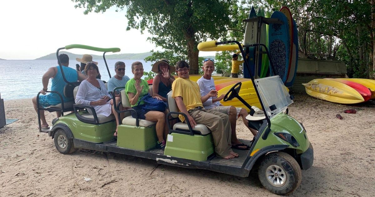 A group of people are sitting in a golf cart on the beach.