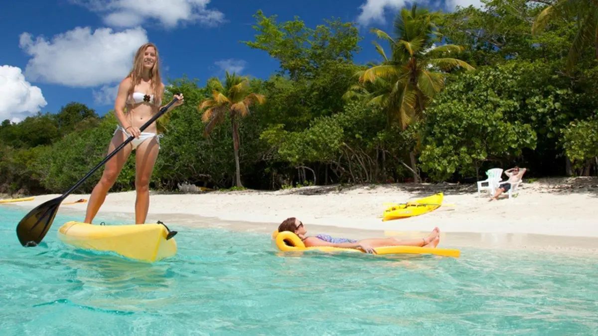 A woman in a bikini is standing on a paddle board in the ocean.