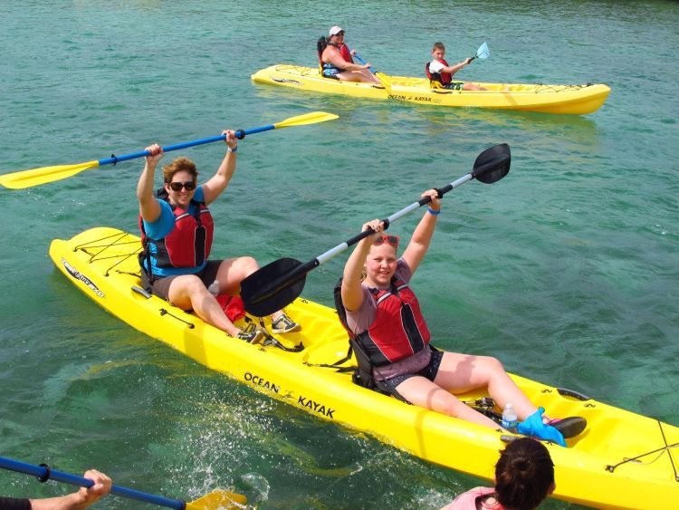 A group of people are paddling yellow kayaks in the water