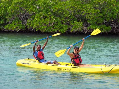 Two people are paddling a yellow kayak in the water.
