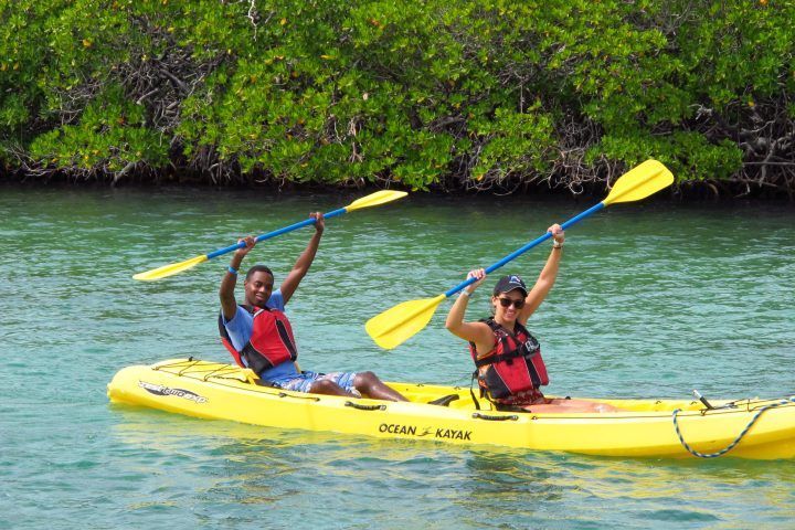 Two people are paddling a yellow kayak in the water.