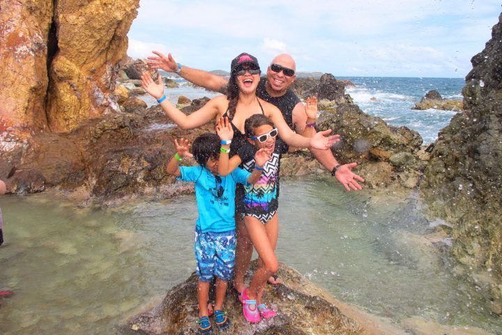 A family is posing for a picture on a rocky beach.