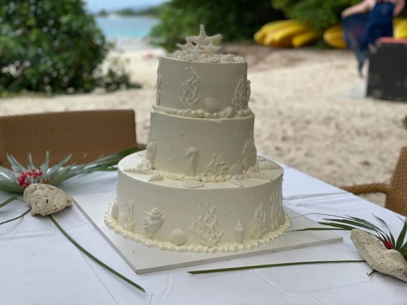 A white wedding cake is sitting on top of a white table.