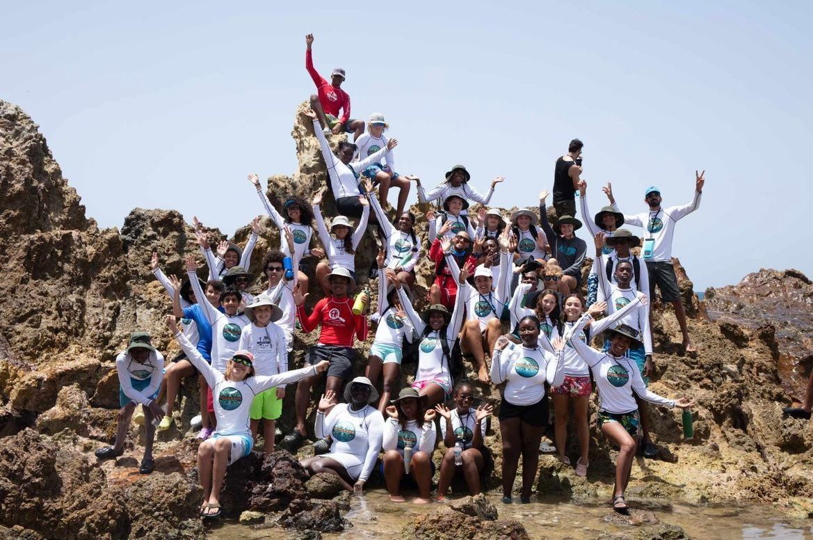 A group of people are posing for a picture on top of a rocky hill.