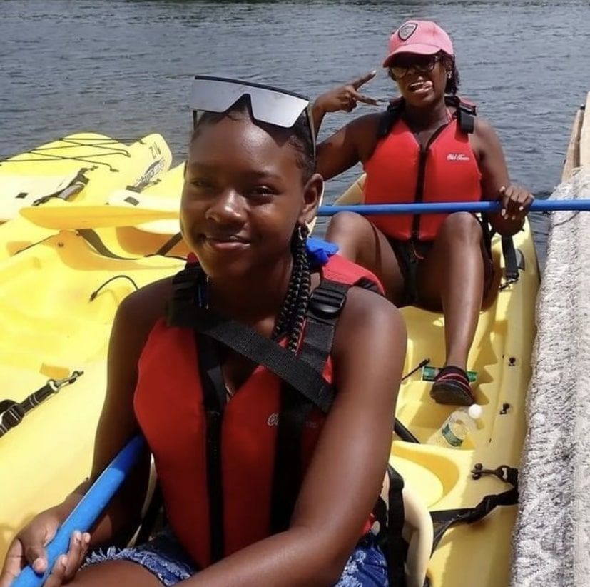 A woman in a red vest is sitting in a yellow kayak