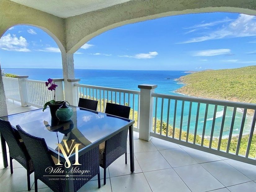 A table and chairs on a balcony overlooking the ocean