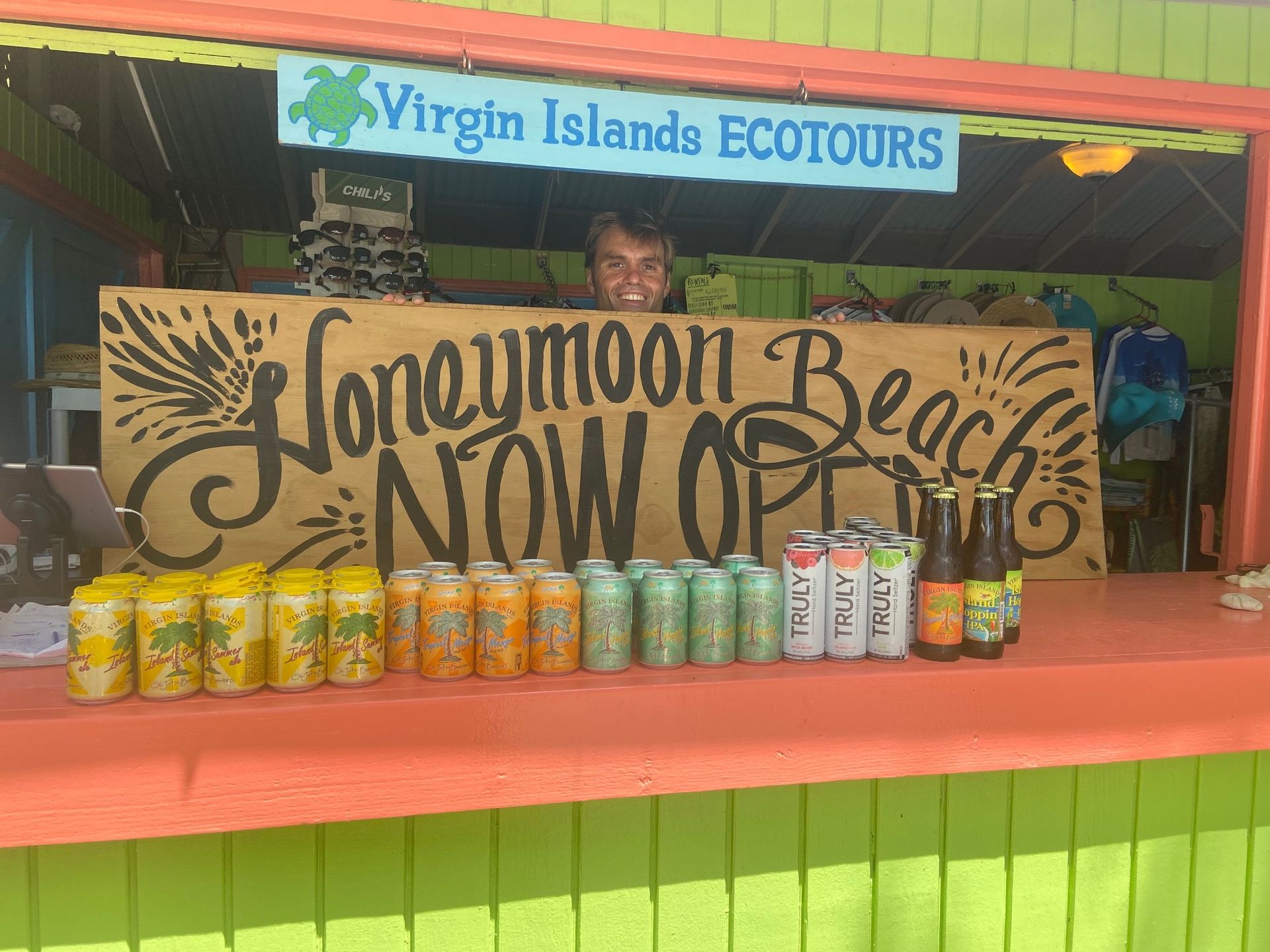 A man is standing behind a counter with a sign that says honeymoon beach now open.