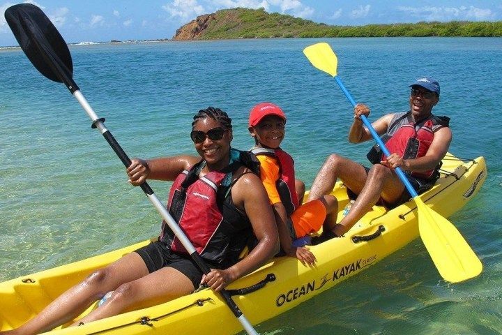 Three people are in a yellow ocean kayak