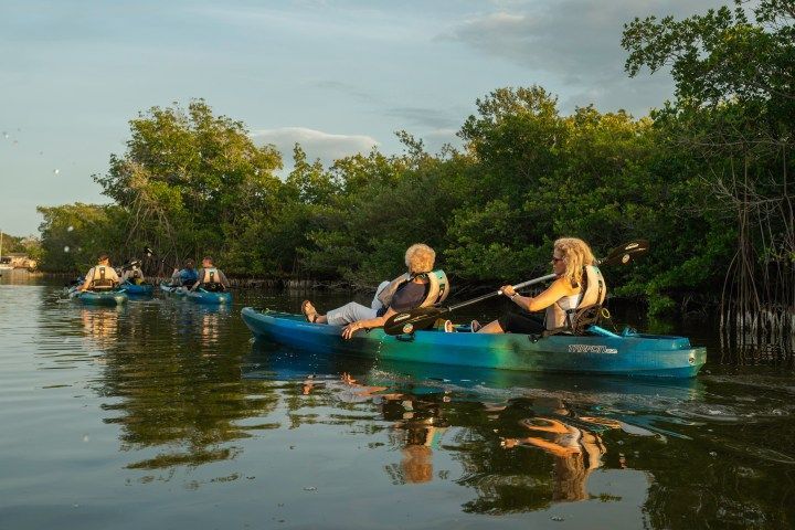 A person is paddling a kayak on a lake at sunset