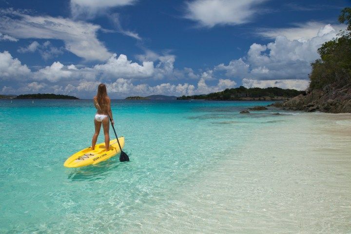 A person kayaks in the aqua colored water of St John