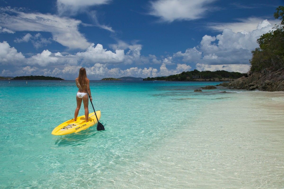 A woman is standing on a paddle board in the ocean.