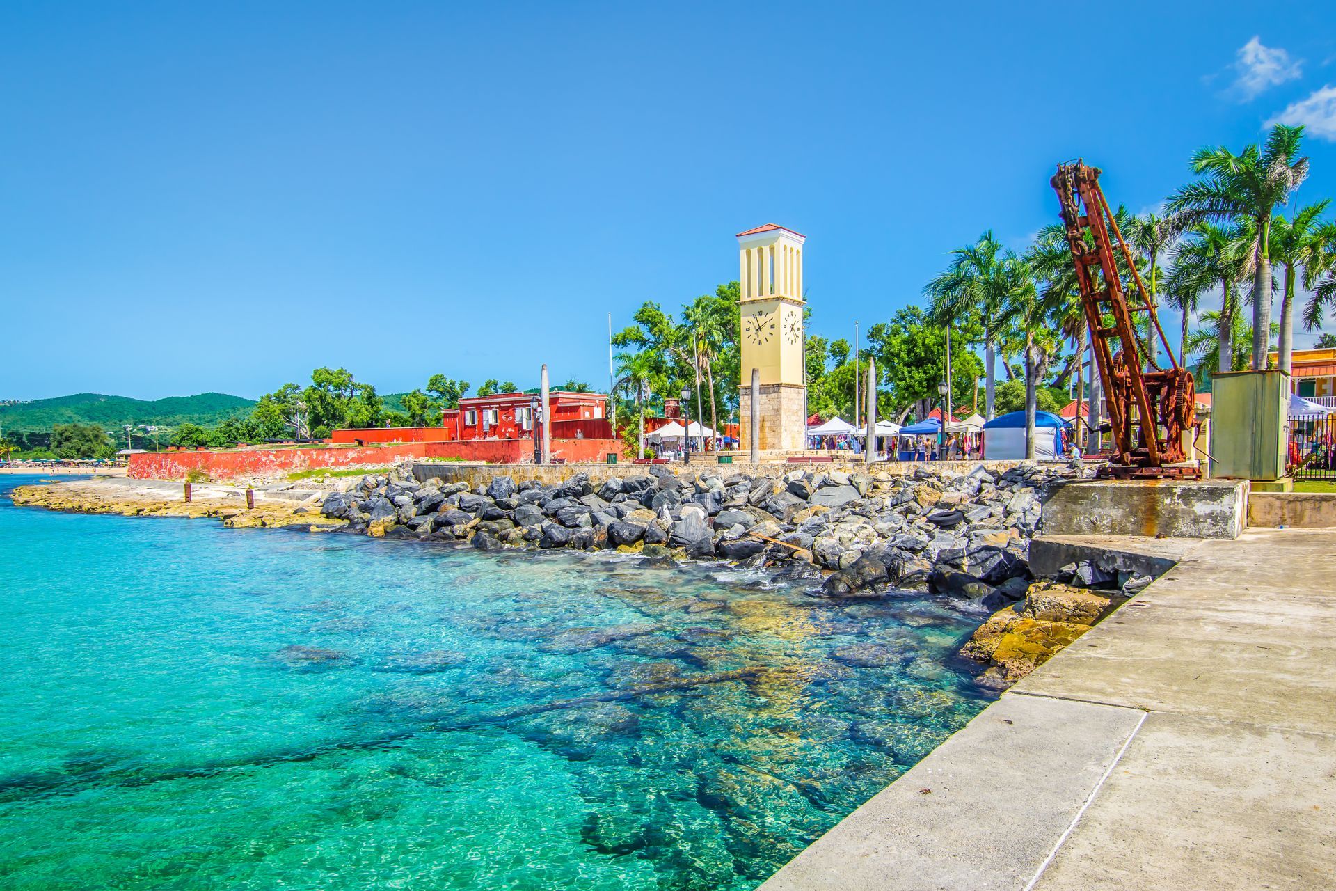 There is a clock tower on the shore of the ocean.