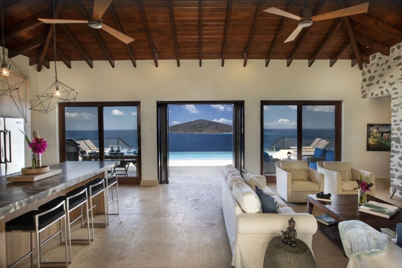 A living room with a ceiling fan and a view of the ocean