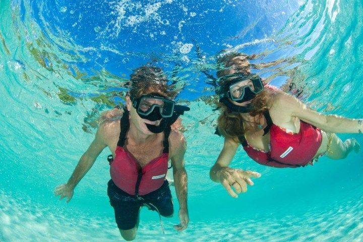 A man and a woman are swimming underwater in the ocean.