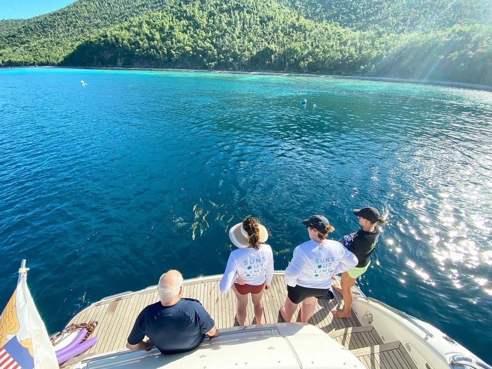 A group of people are sitting on the back of a boat looking out over a body of water.