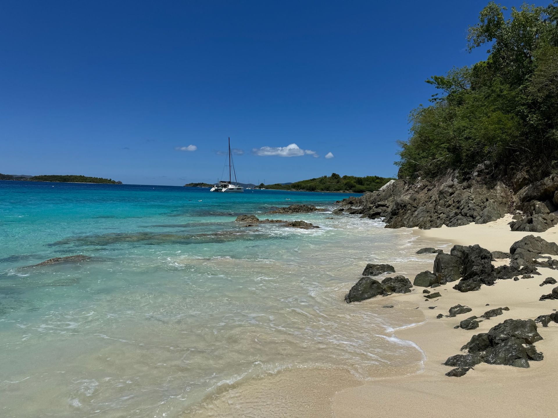A beach with a sailboat in the distance