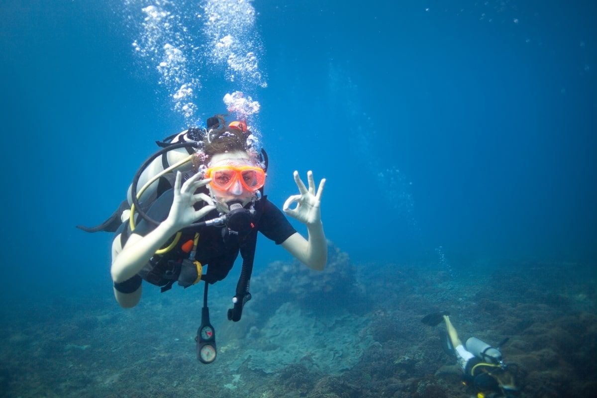 A scuba diver is giving the ok sign in the ocean.