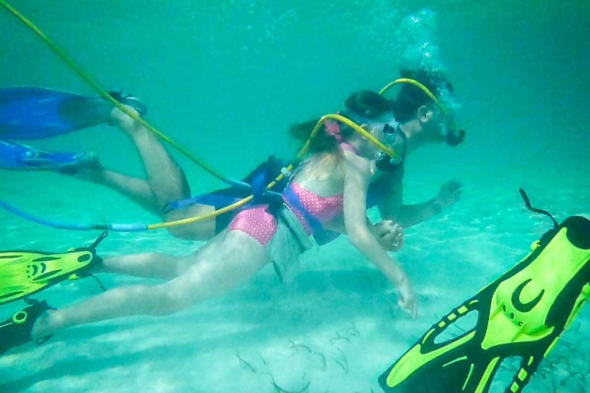 A woman in a pink bikini is swimming underwater with a scuba diver.