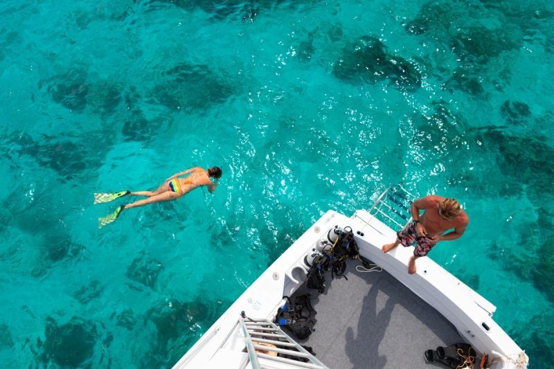 A man and a woman are swimming in the ocean on a boat.