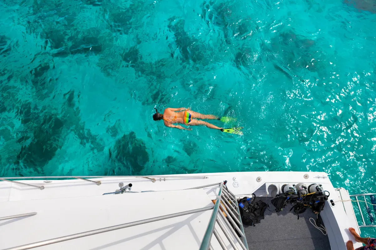 A man is swimming in the ocean on a boat.