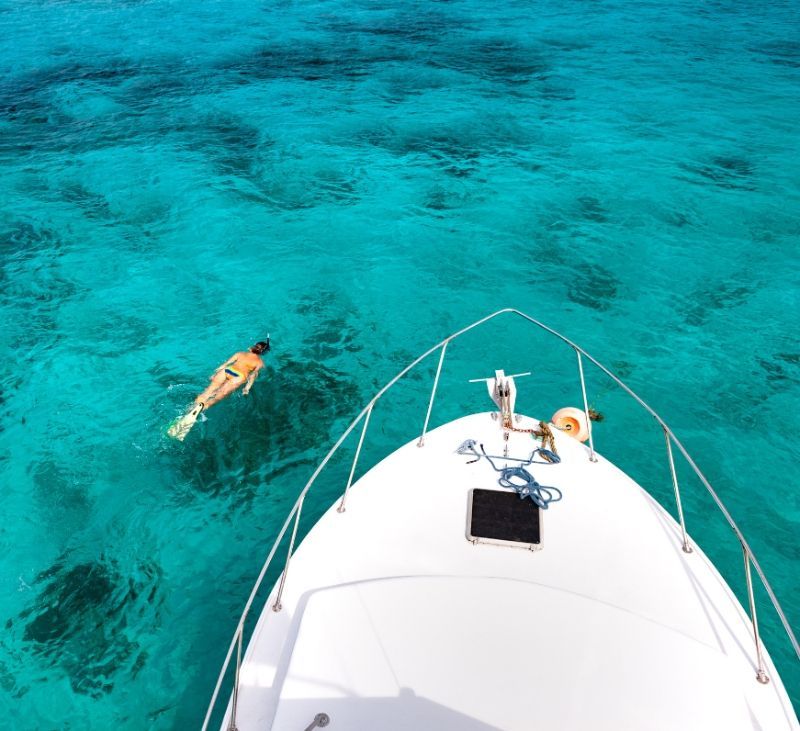 A person is swimming in the ocean next to a boat