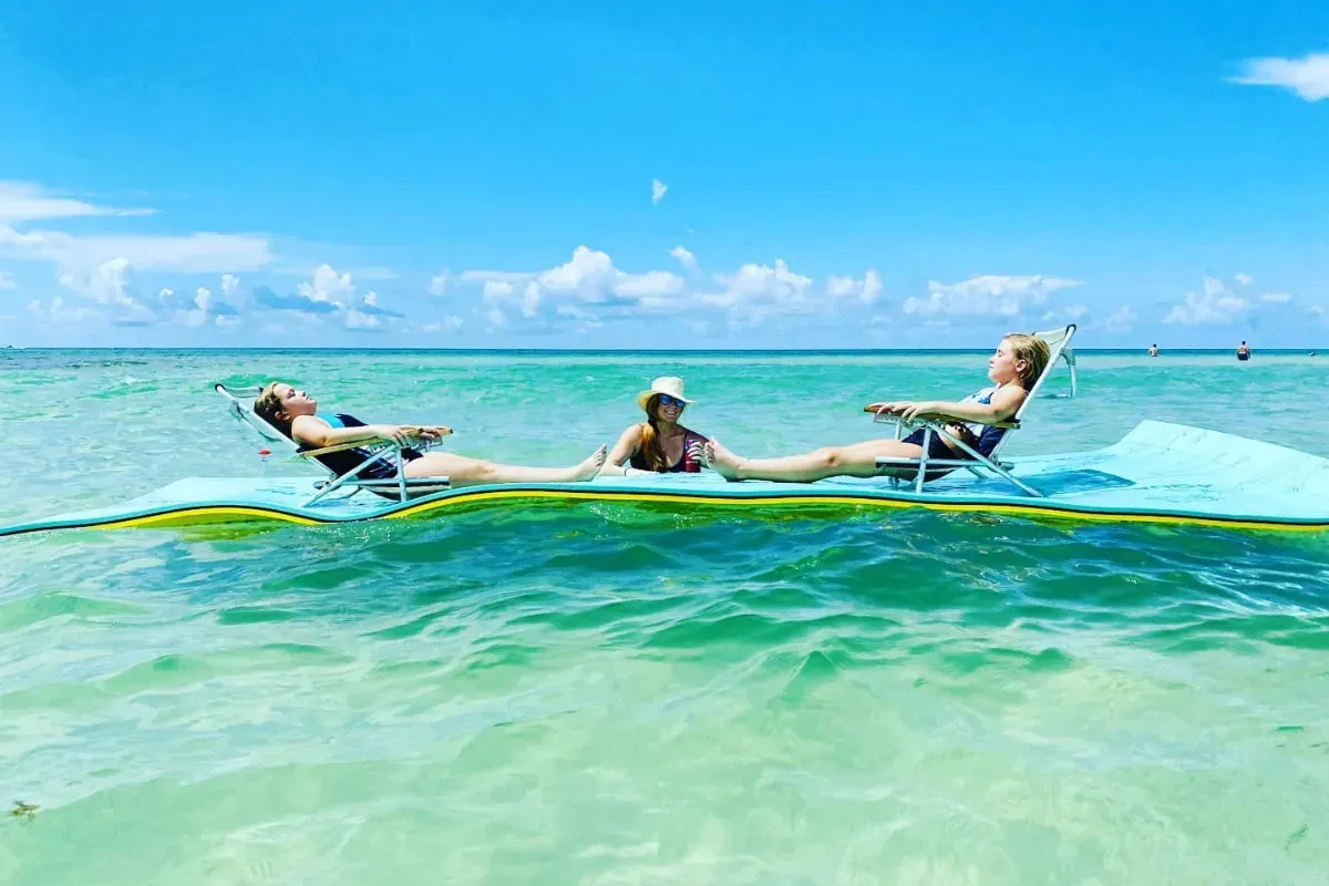 Three women are laying on a raft in the ocean.