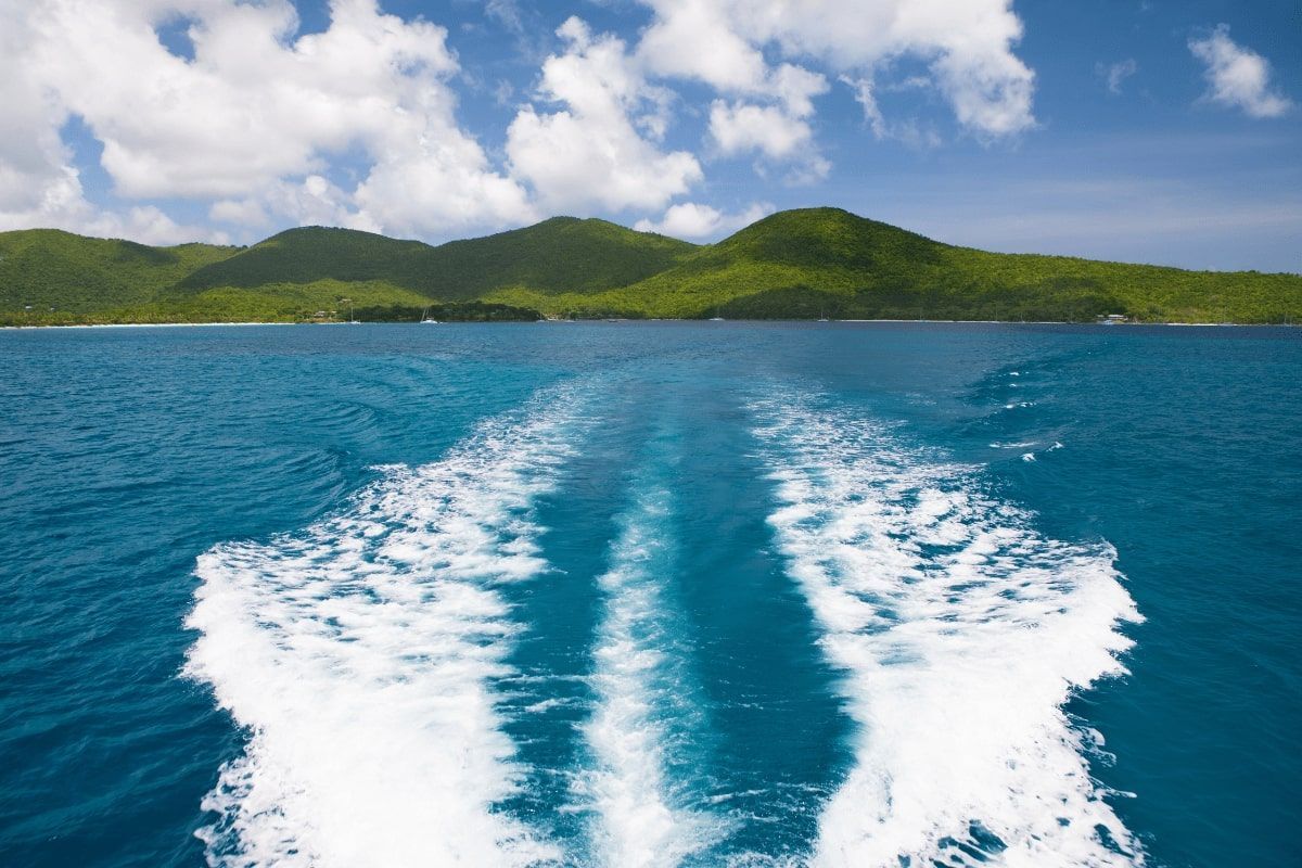 A boat is going through a body of water with mountains in the background