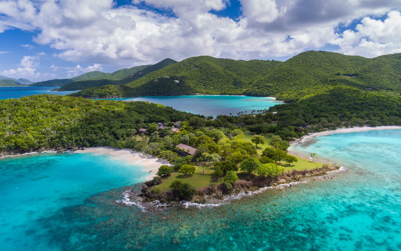 An aerial view of a small island in the middle of the ocean surrounded by mountains.