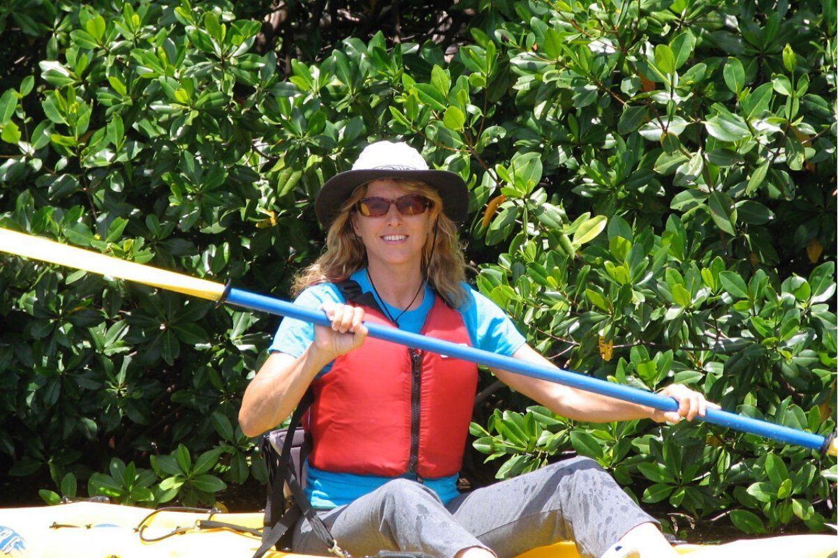 A woman is sitting in a kayak holding a paddle